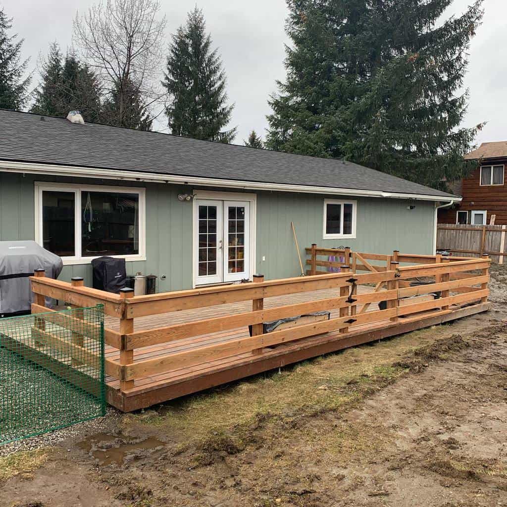 Rustic pallet fence enclosing a backyard deck, offering a simple and functional barrier with a natural wood finish for a cozy outdoor space