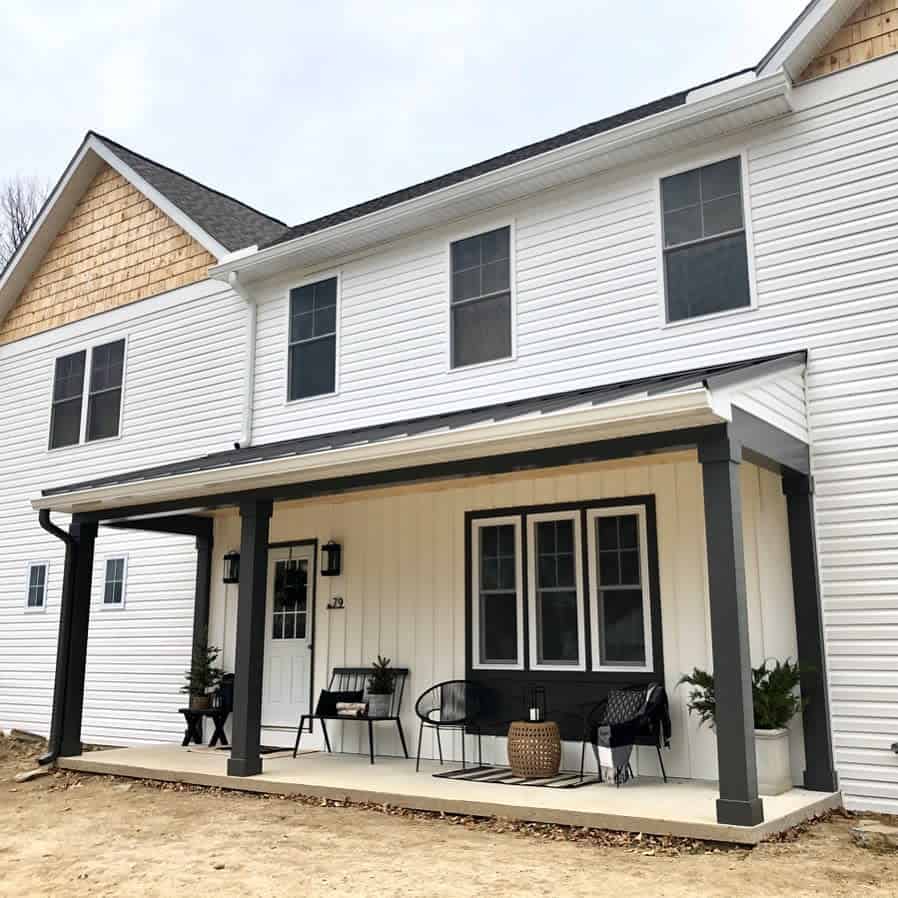 Modern farmhouse porch with black columns, cozy seating, and neutral decor, creating a stylish yet inviting outdoor space