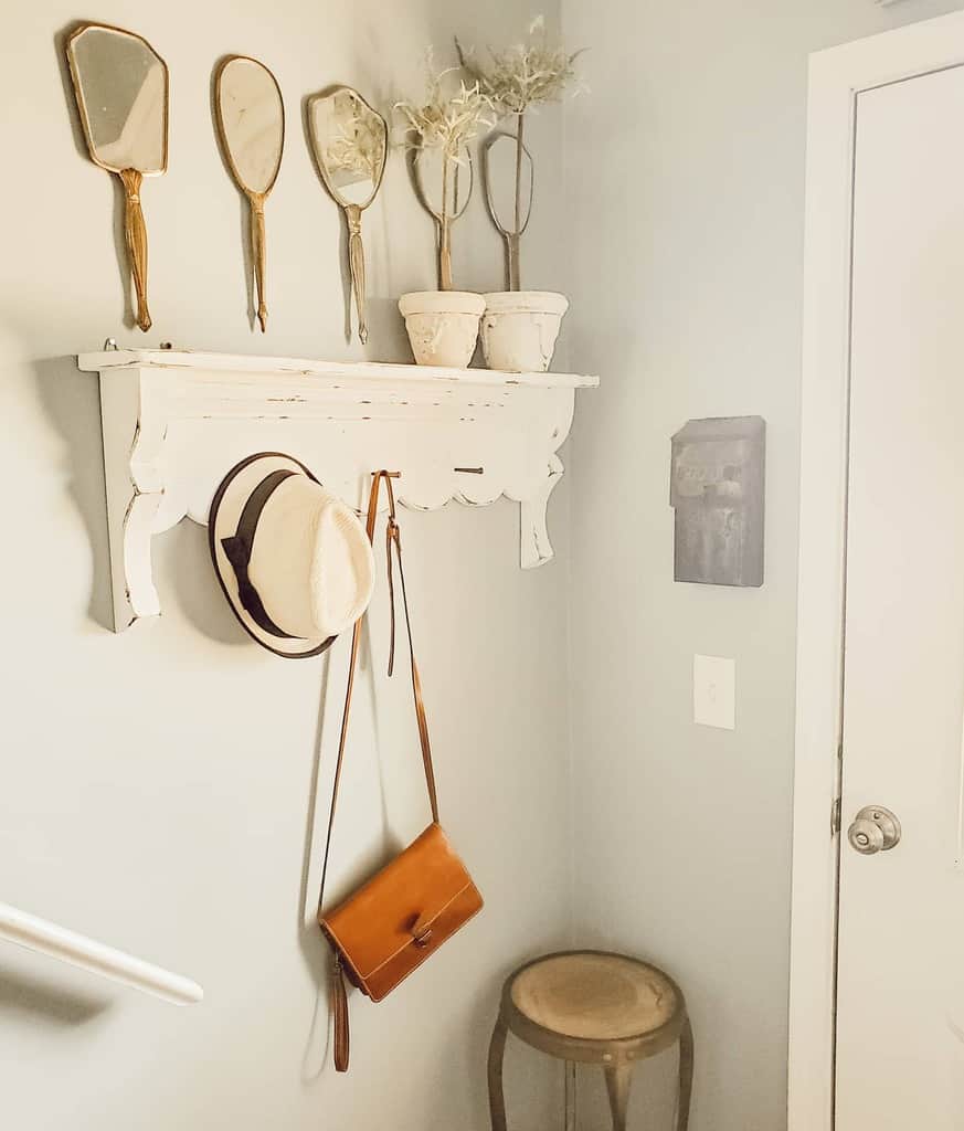 Vintage farmhouse entryway with distressed wall shelf, antique hand mirrors, potted plants, and stylish hanging accessories