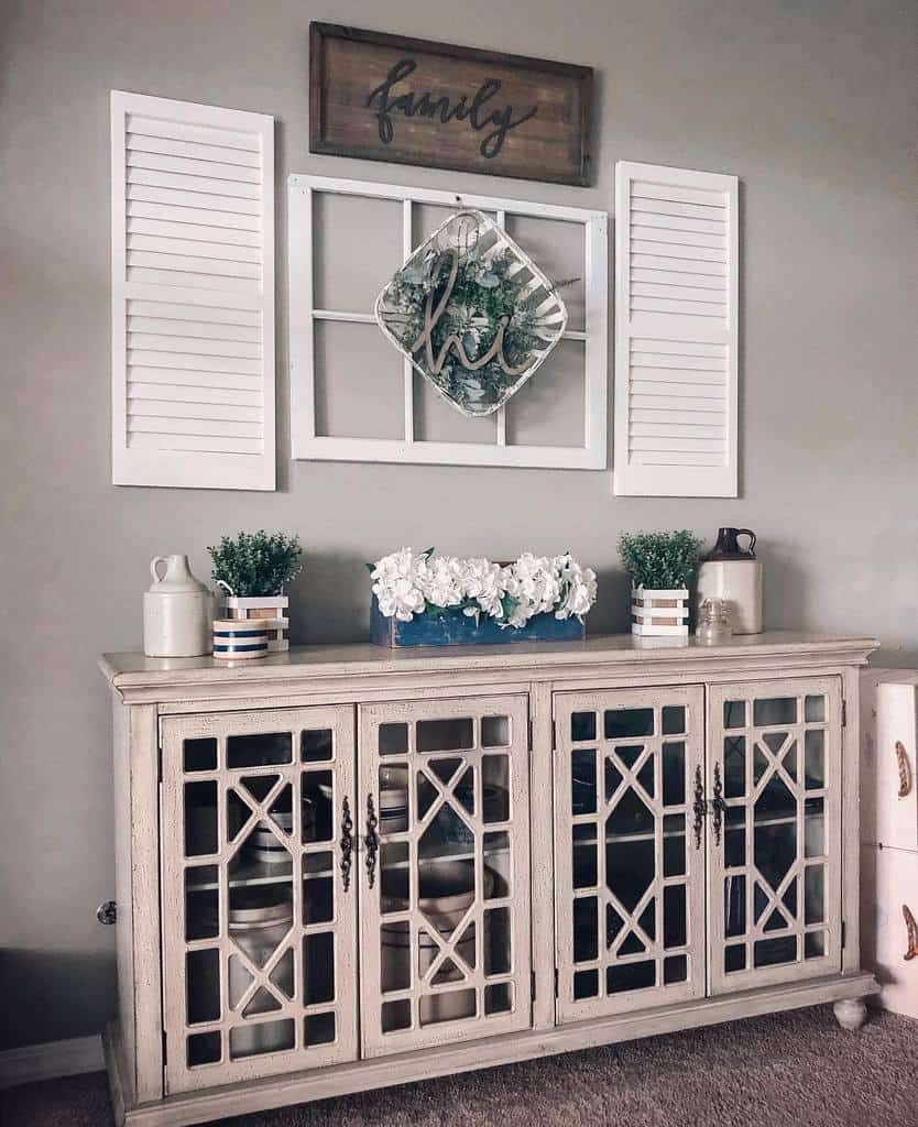 Farmhouse-style entryway with a distressed wood console, decorative glass doors, vintage accents, and a welcoming 'family' wall display