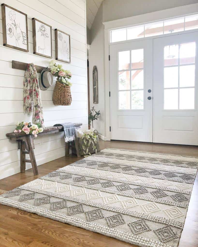 Bright farmhouse entryway with shiplap walls, a rustic wooden bench, floral decor, woven accents, and a cozy patterned rug