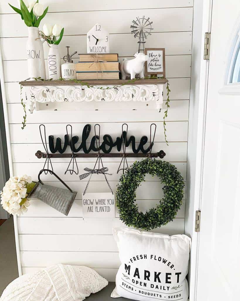 Farmhouse entryway with shiplap walls, a vintage-style shelf, greenery accents, a 'welcome' sign, and rustic decor for a cozy touch