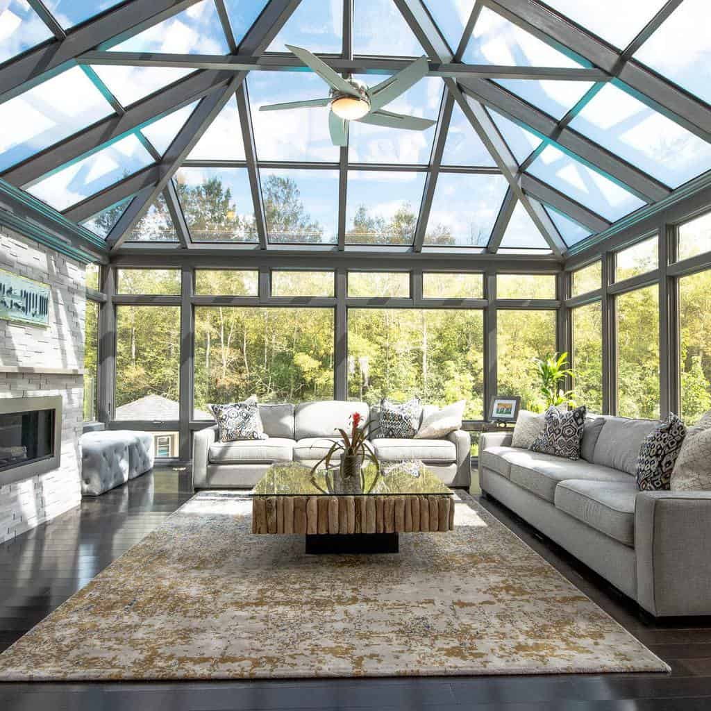 Rustic glass-top coffee table with a natural driftwood base, styled with a decorative vase, set in a bright sunroom with floor-to-ceiling windows