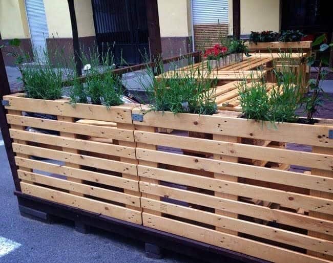 Modern DIY pallet fence with horizontal slats and built-in planters, creating a stylish and functional outdoor seating area