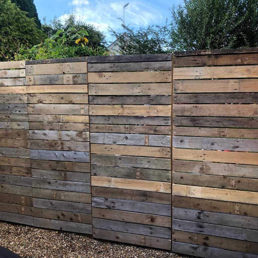 Modern DIY pallet fence with a mix of weathered and natural wood tones, creating a stylish and eco-friendly backyard barrier