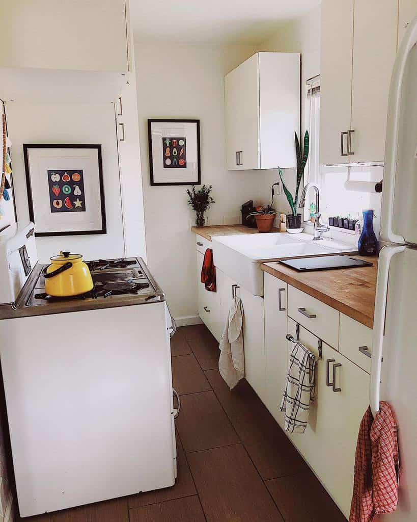 Cozy tiny house kitchen with white cabinets, wooden countertops, and a farmhouse sink. A yellow kettle adds a pop of color.