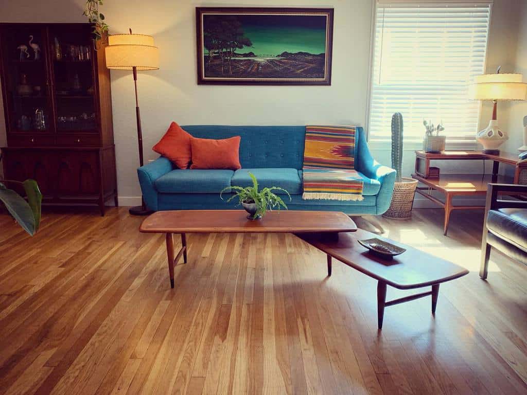 Mid-century modern wooden coffee tables with tapered legs, styled with a small plant and dish, set in a retro-inspired living room with a blue sofa