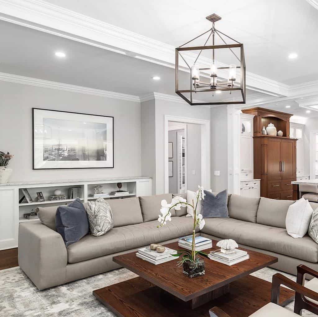 Square wooden coffee table with a rich finish, styled with books, decorative objects, and an orchid, set in a modern living room with a neutral palette