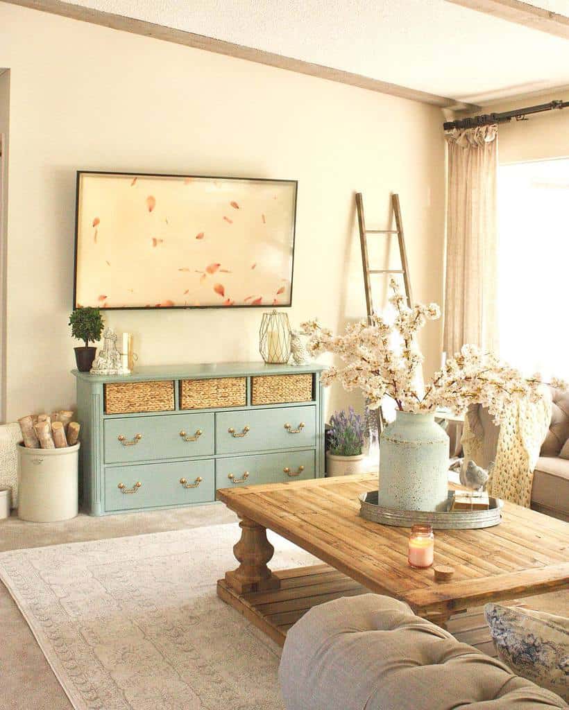 Rustic wooden coffee table with a lower shelf, styled with a vintage vase of flowers, a candle, and decor, set in a cozy farmhouse-style living room