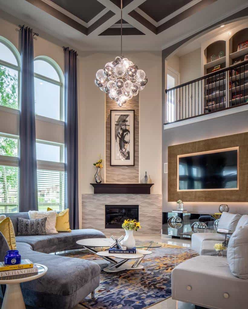 Modern glass coffee table with a sculptural chrome base, styled with books and a vase, set in a luxurious living room with high ceilings and elegant decor