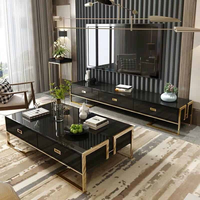 Luxurious black and gold coffee table with sleek storage drawers, styled with books, decor, and greenery, set in a modern living room with a matching TV console