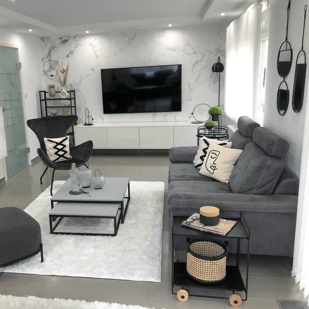 Modern nesting coffee tables with gray tops and black metal frames, styled with vases and decor, set in a sleek monochrome living room