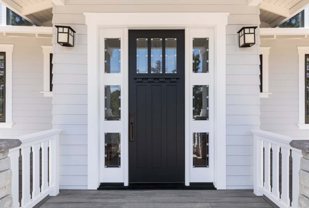 Black front door with white trim, flanked by windows, on a gray house