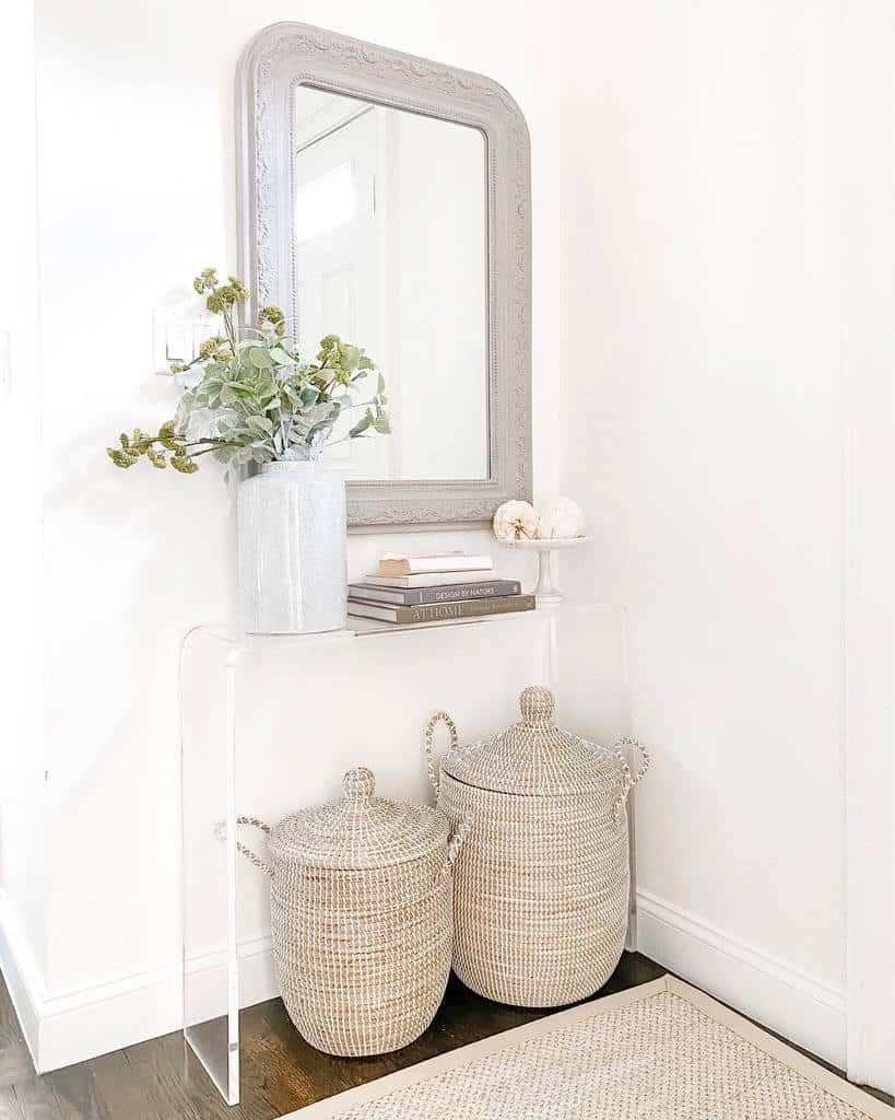 Bright and airy entryway with a clear acrylic console, woven storage baskets, a vintage mirror, and soft neutral decor for a modern touch