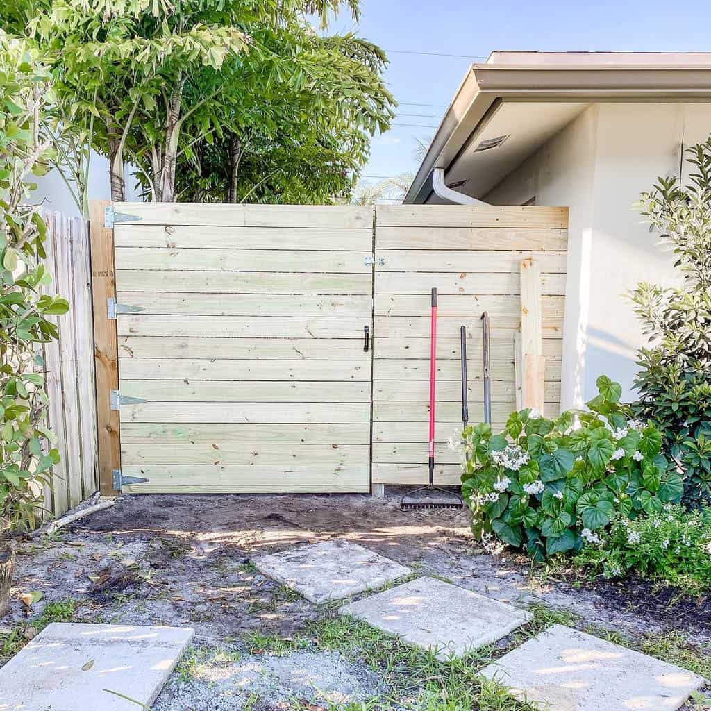 Light wooden pallet gate with a modern design, blending seamlessly into a lush garden setting with neatly arranged stepping stones