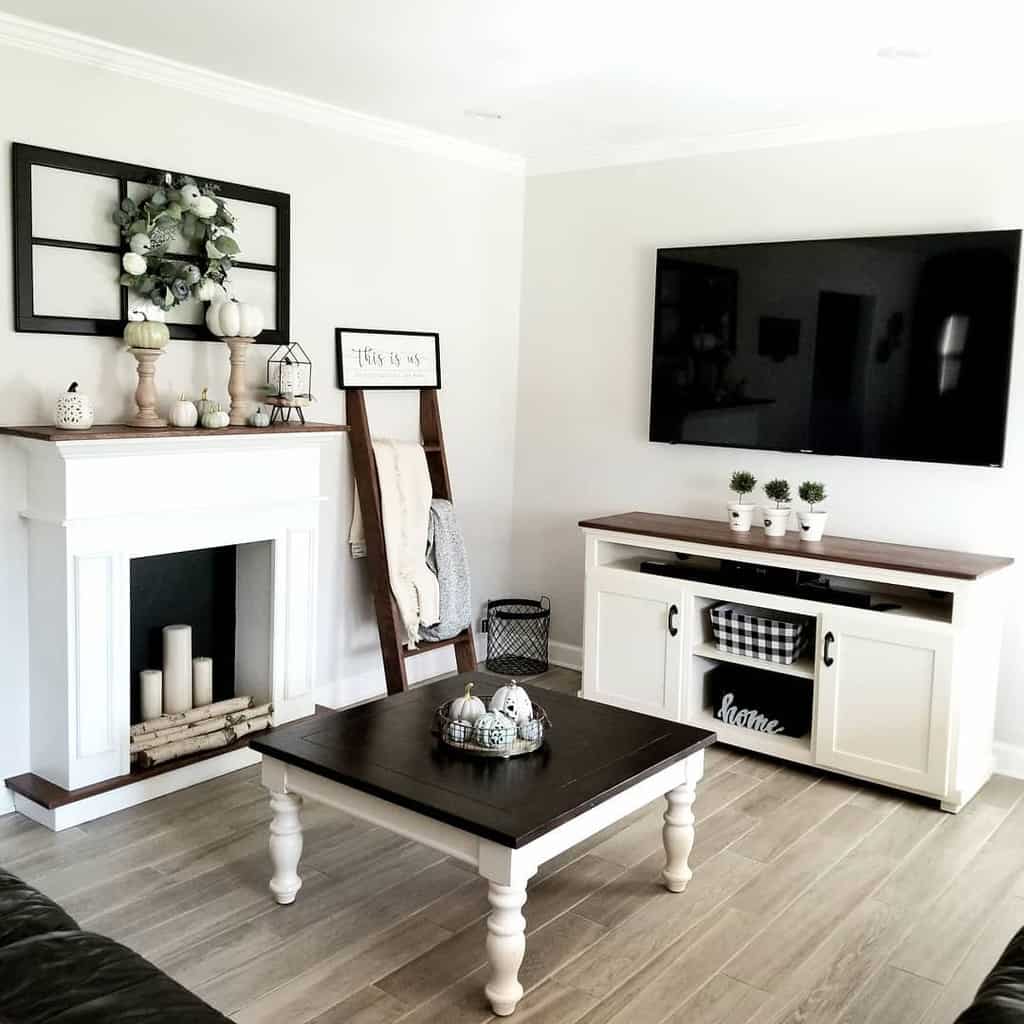 Two-tone farmhouse coffee table with a dark wooden top and white turned legs, styled with decorative pumpkins, set in a cozy neutral-toned living room