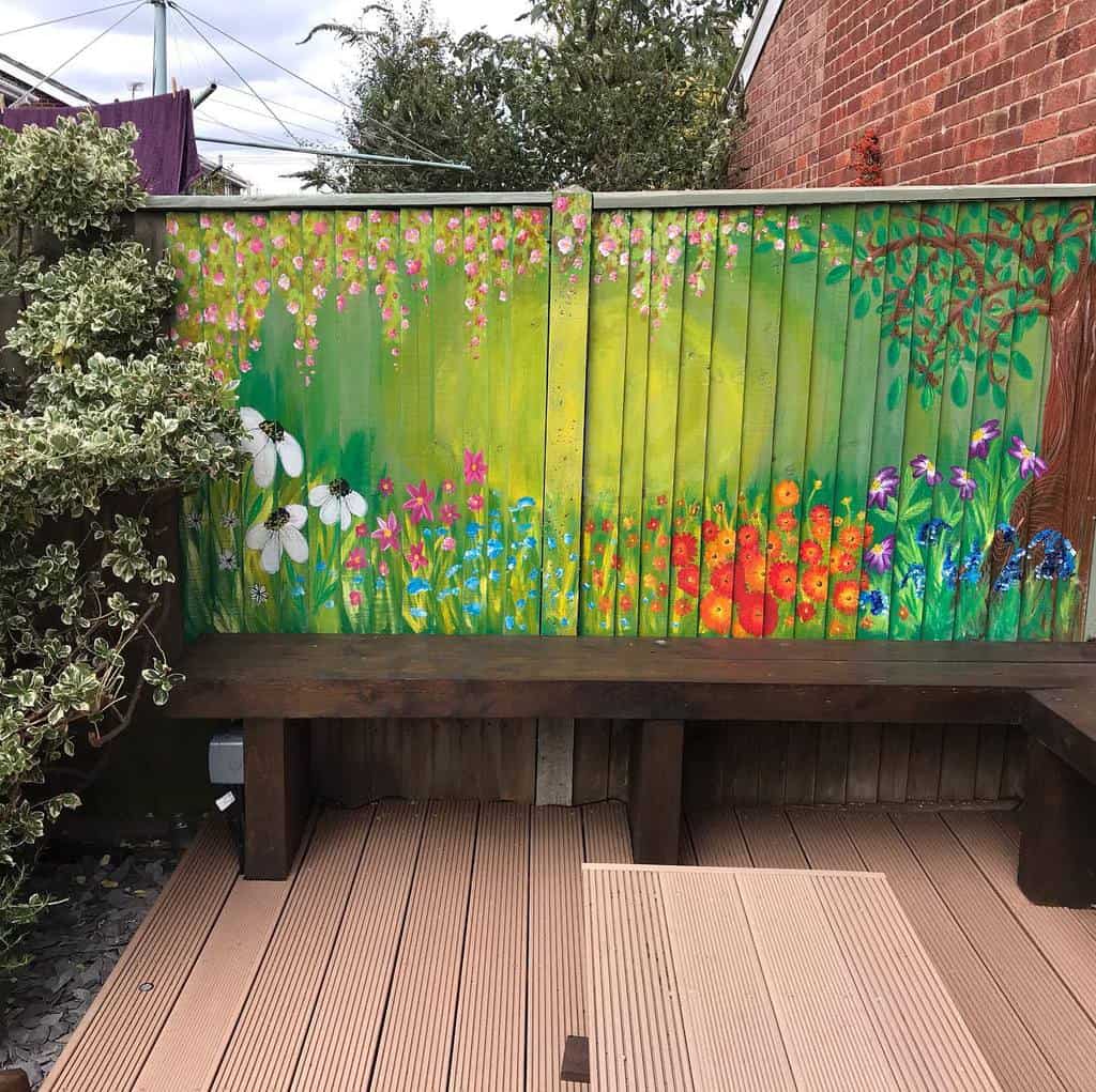 Vibrant hand-painted garden scene on a wooden fence, featuring colorful flowers, greenery, and a tree, adding charm to the outdoor seating area