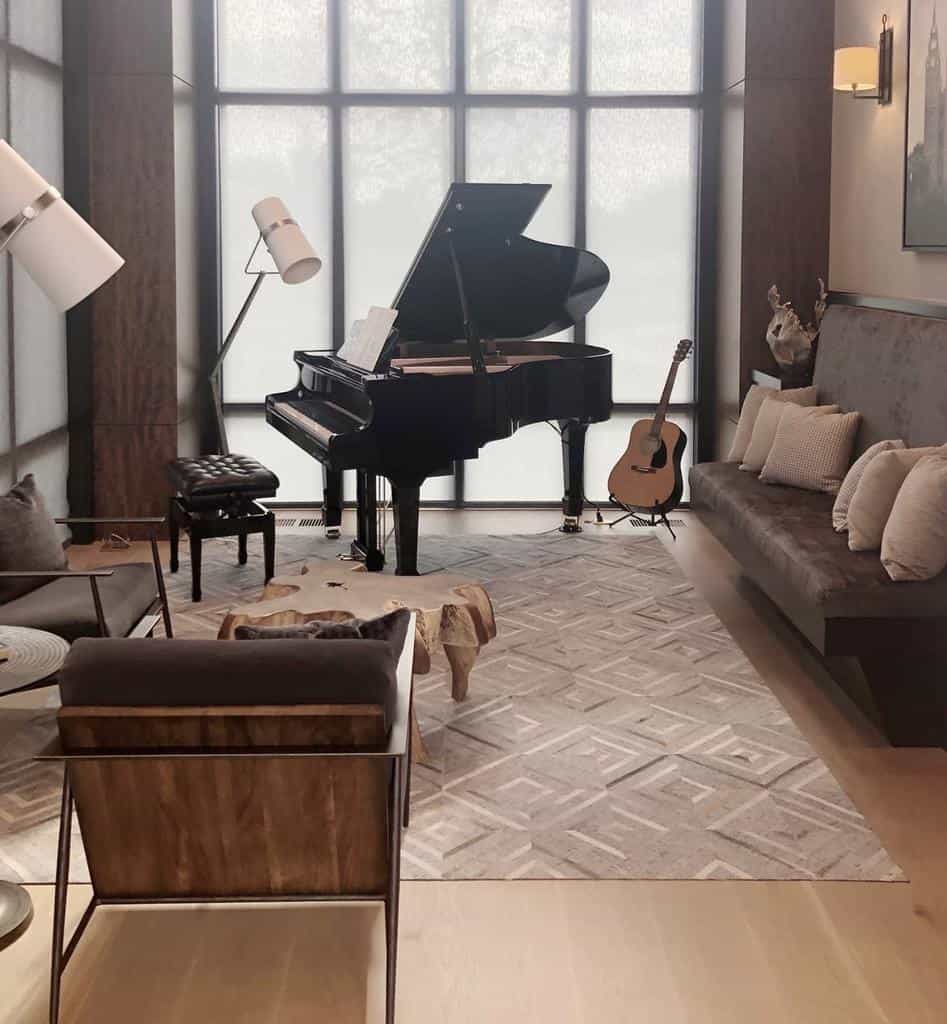 Luxurious music room with a grand piano, acoustic guitar, modern lighting, plush seating, and elegant neutral decor