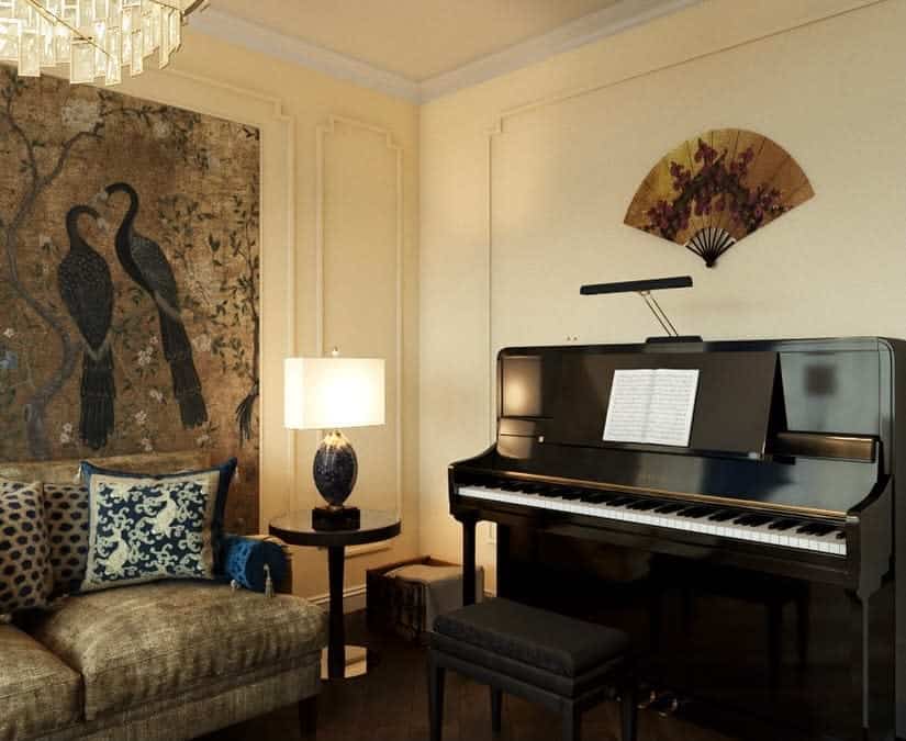 Elegant music room with an upright piano, ornate wall art, plush seating, warm lighting, and a sophisticated Asian-inspired decor theme