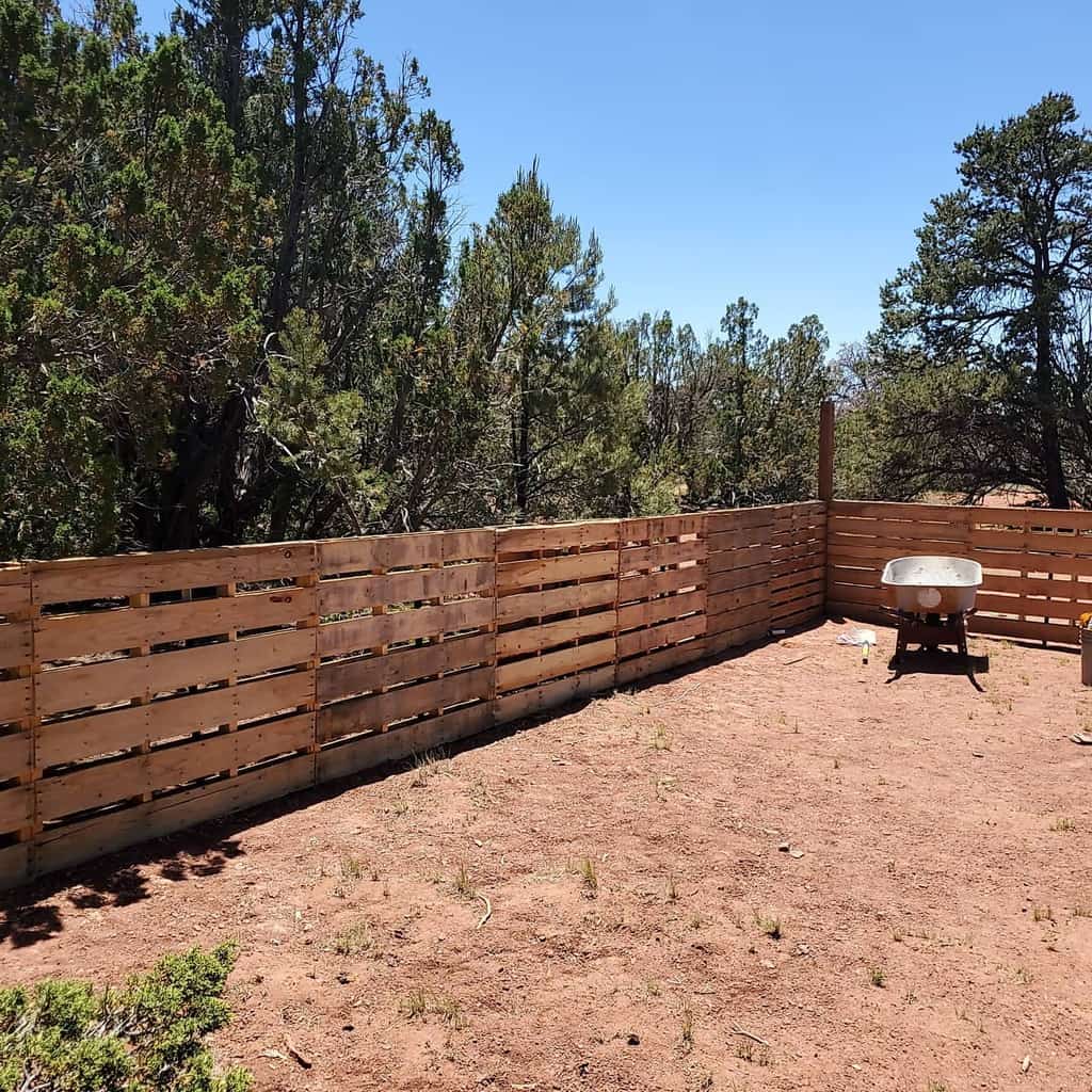 Simple DIY pallet fence enclosing a dry, rural landscape, creating a rustic and budget-friendly barrier against the natural surroundings