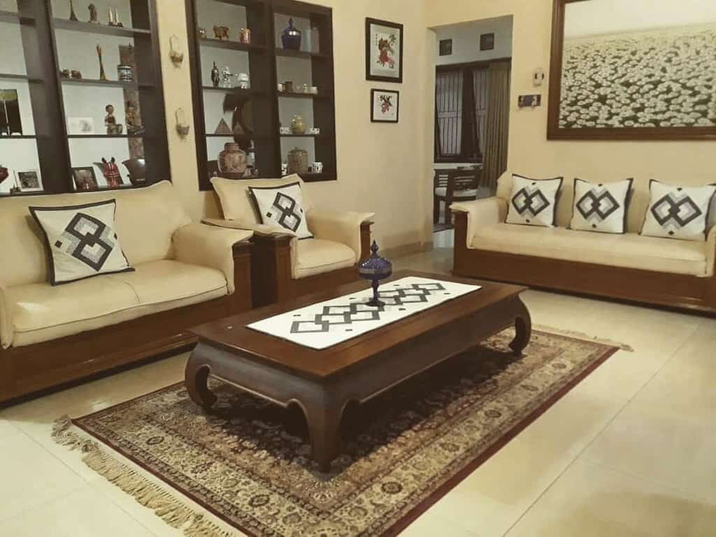 Elegant wooden coffee table with curved legs, styled with a decorative runner and centerpiece, set in a warm-toned living room with traditional decor