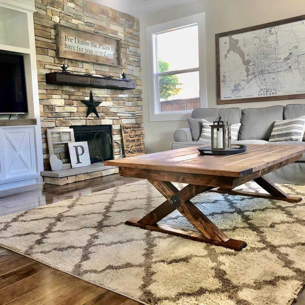 Cozy living room with stone fireplace, large wooden coffee table, map art on wall, and neutral decor, rug and sunlight from window