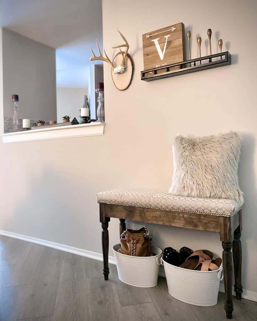 Rustic entryway with a wooden bench, faux fur pillow, wall-mounted decor, antler accent, and stylish storage bins for shoes and bags