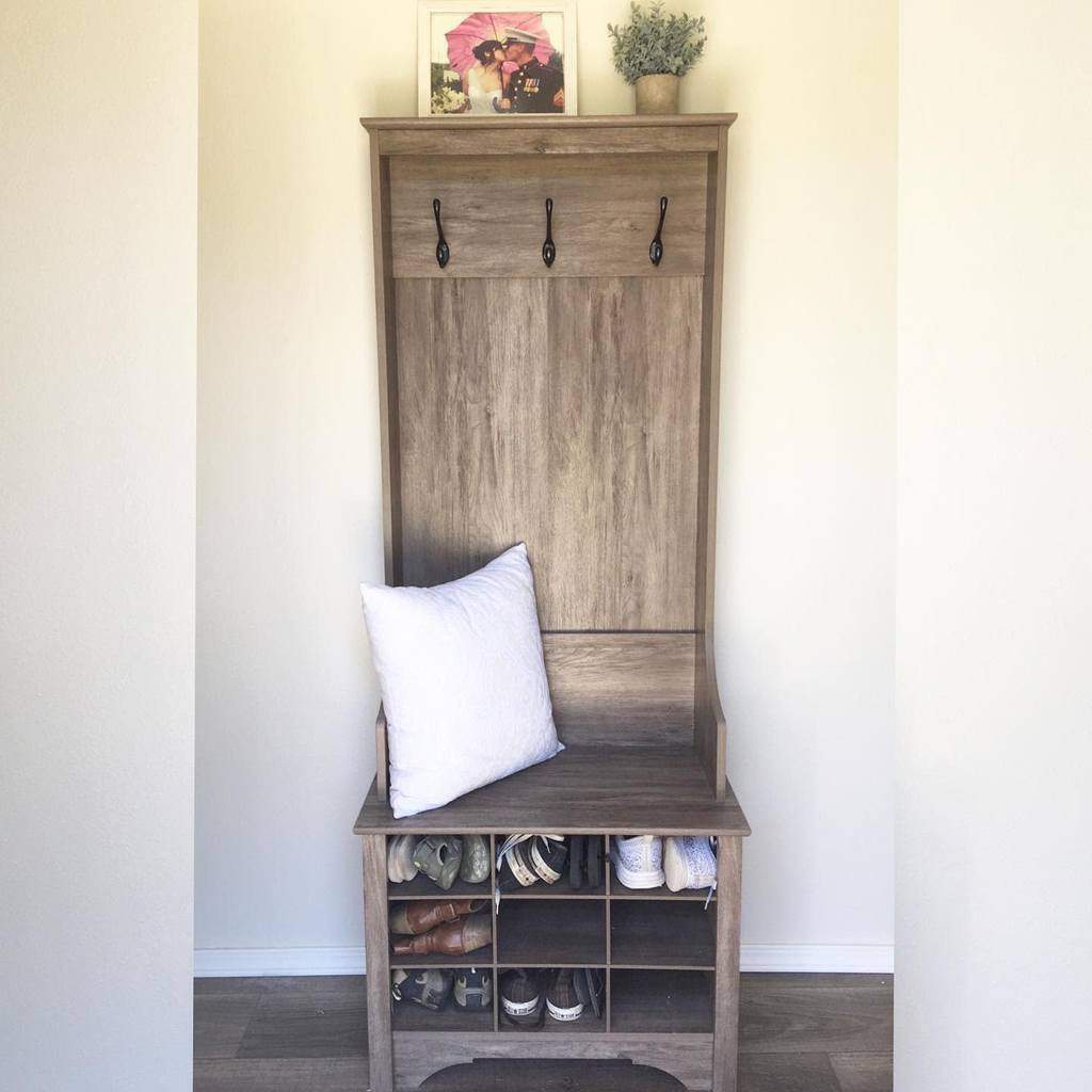 Rustic entryway with a wooden hall tree bench, built-in shoe storage, wall hooks, and simple decor for a functional and cozy space