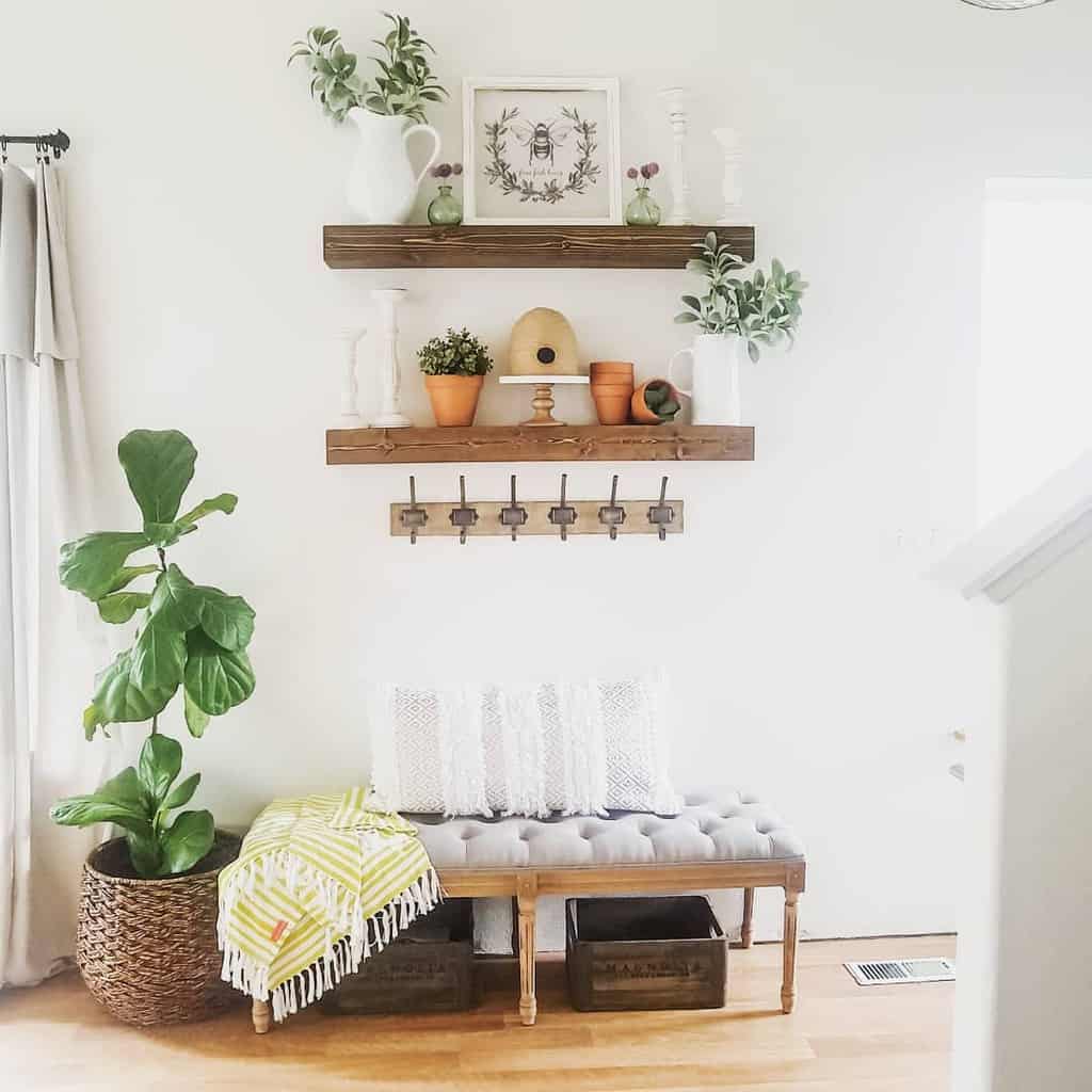 Bright farmhouse entryway with a tufted bench, floating wooden shelves, greenery, rustic wall hooks, and a woven planter for a cozy touch