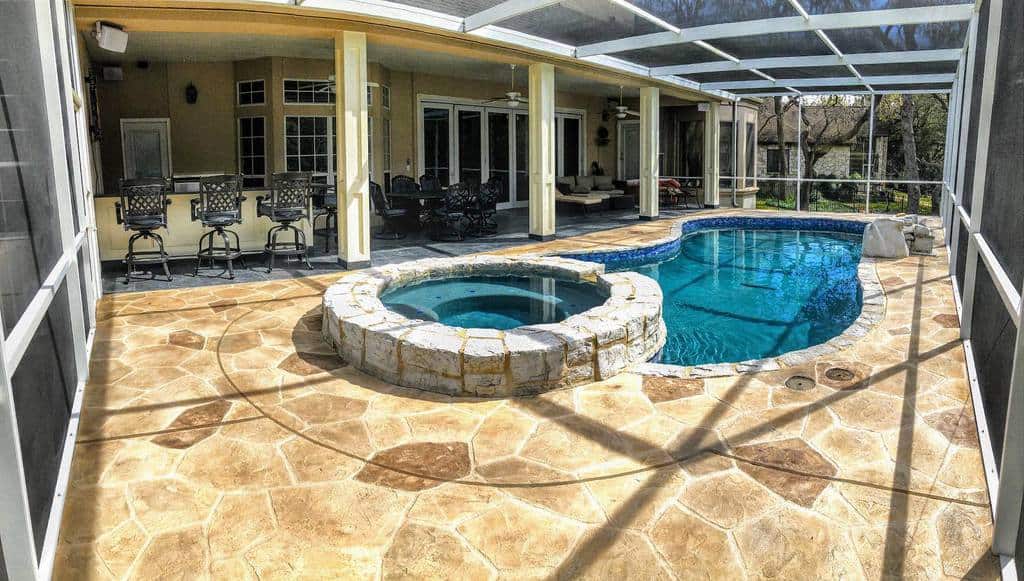 Outdoor patio with a stone hot tub and a small swimming pool, seating under a covered area, and the space is screened-in