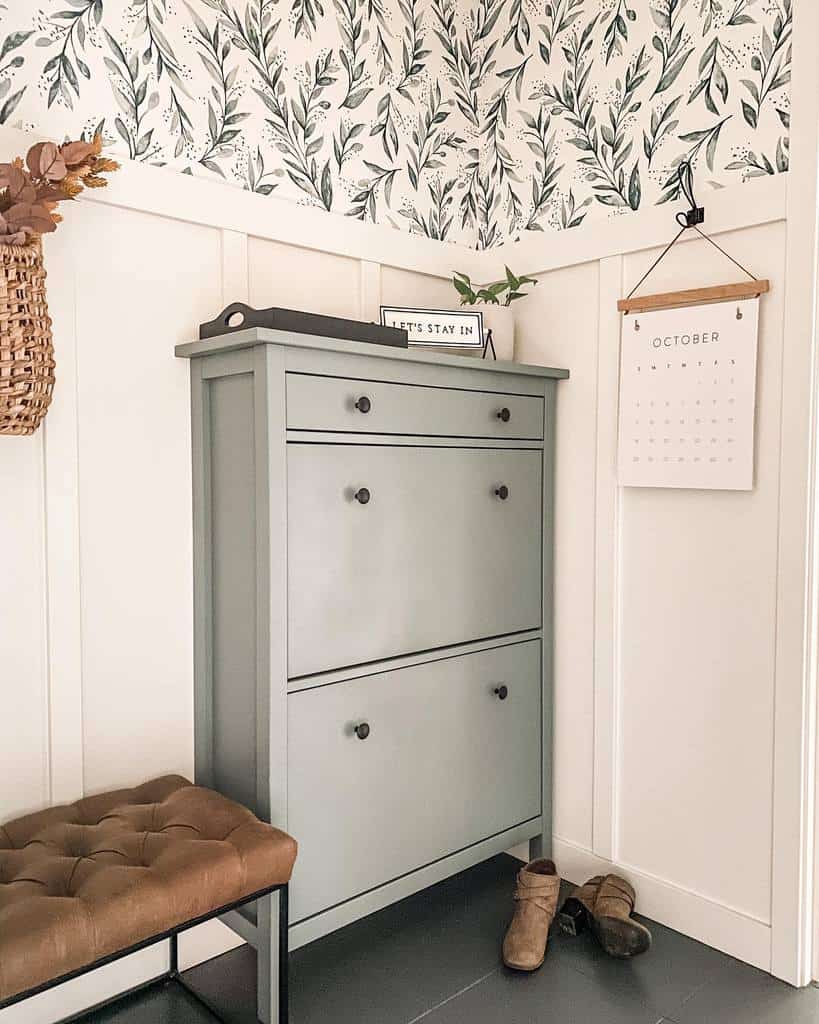 Stylish entryway with a sage green shoe cabinet, botanical wallpaper, a tufted bench, and cozy decor for a welcoming feel