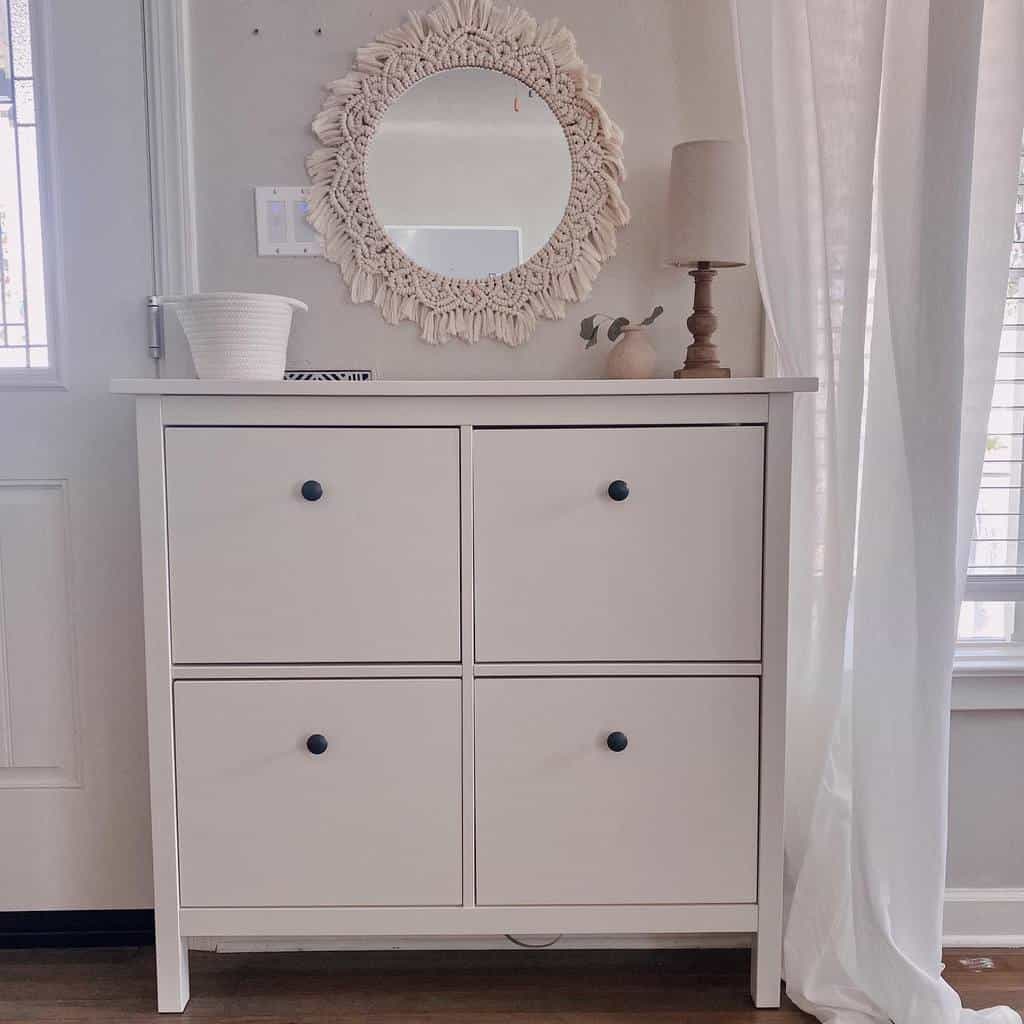 Boho-style entryway with a white shoe cabinet, macrame-framed mirror, soft neutral decor, and natural light for an airy feel