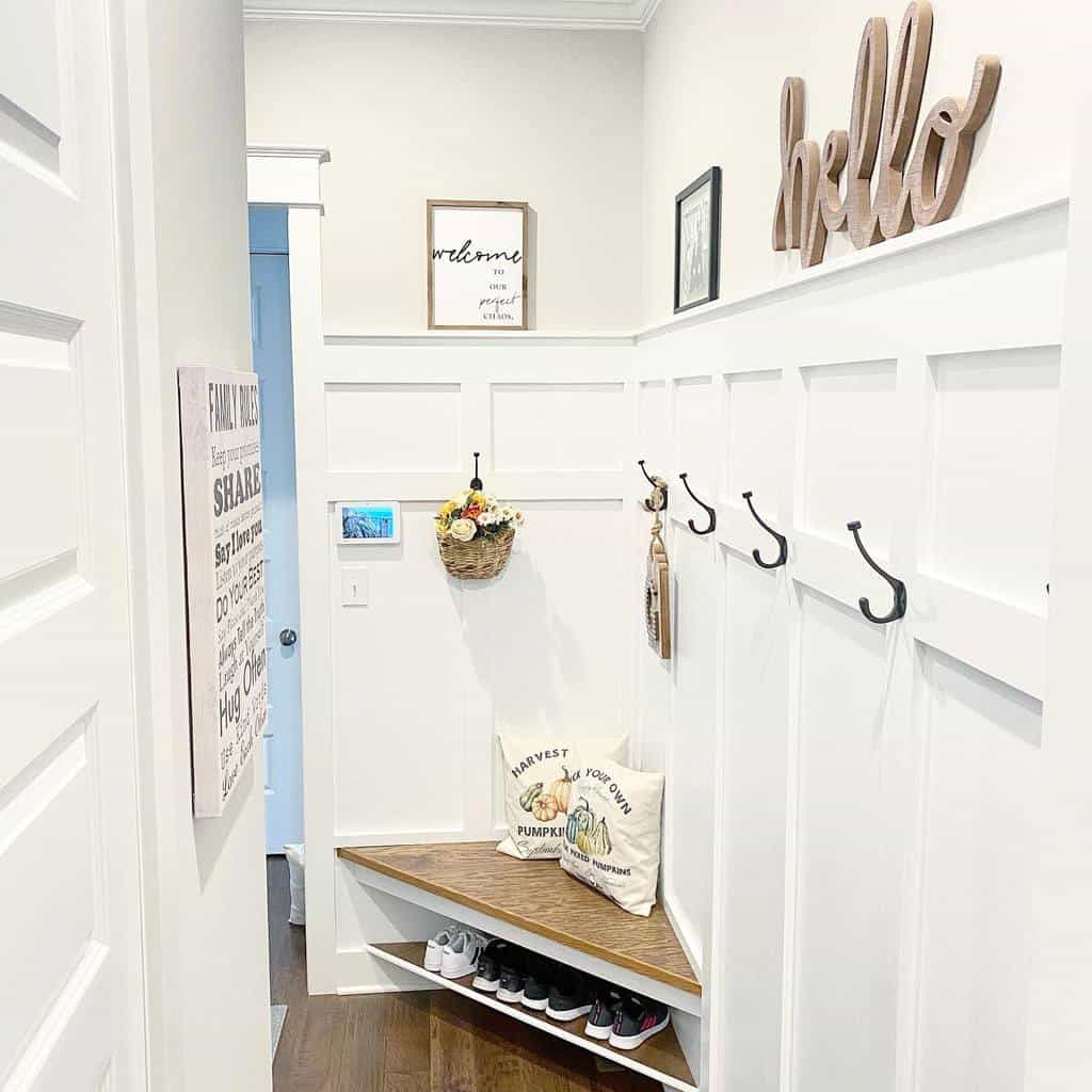 Bright and welcoming entryway with built-in corner seating, shoe storage, wall hooks, and farmhouse-inspired decor for a cozy touch