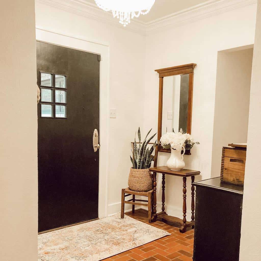 Warm and elegant entryway with a black front door, vintage wooden furniture, a woven planter, floral accents, and a cozy area rug