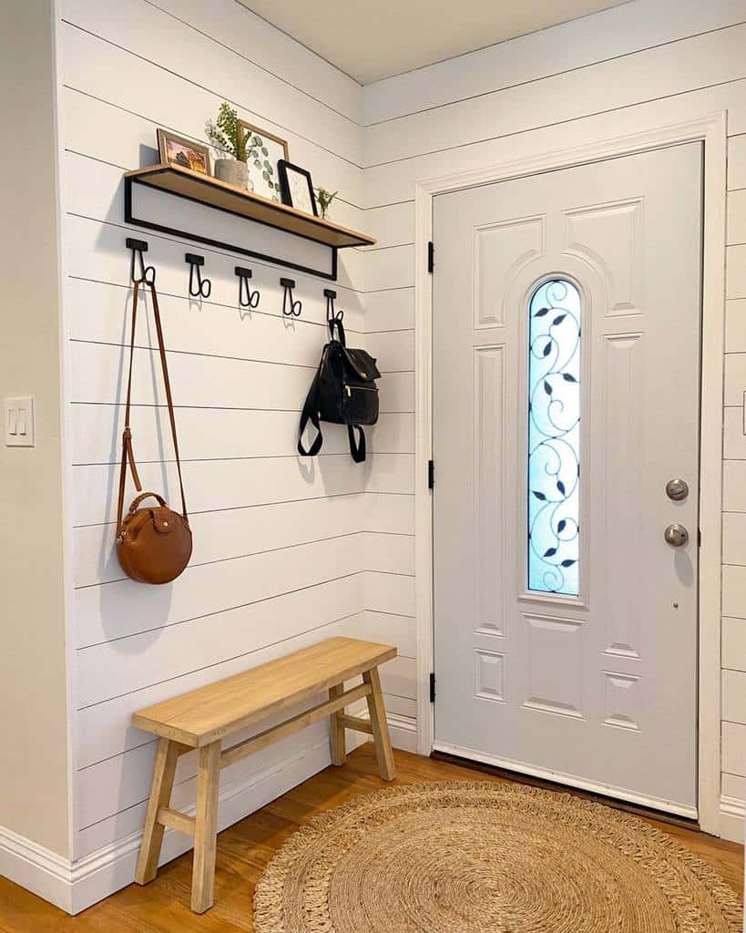 Modern farmhouse entryway with shiplap walls, a wooden bench, black metal wall hooks, a floating shelf, and a woven jute rug