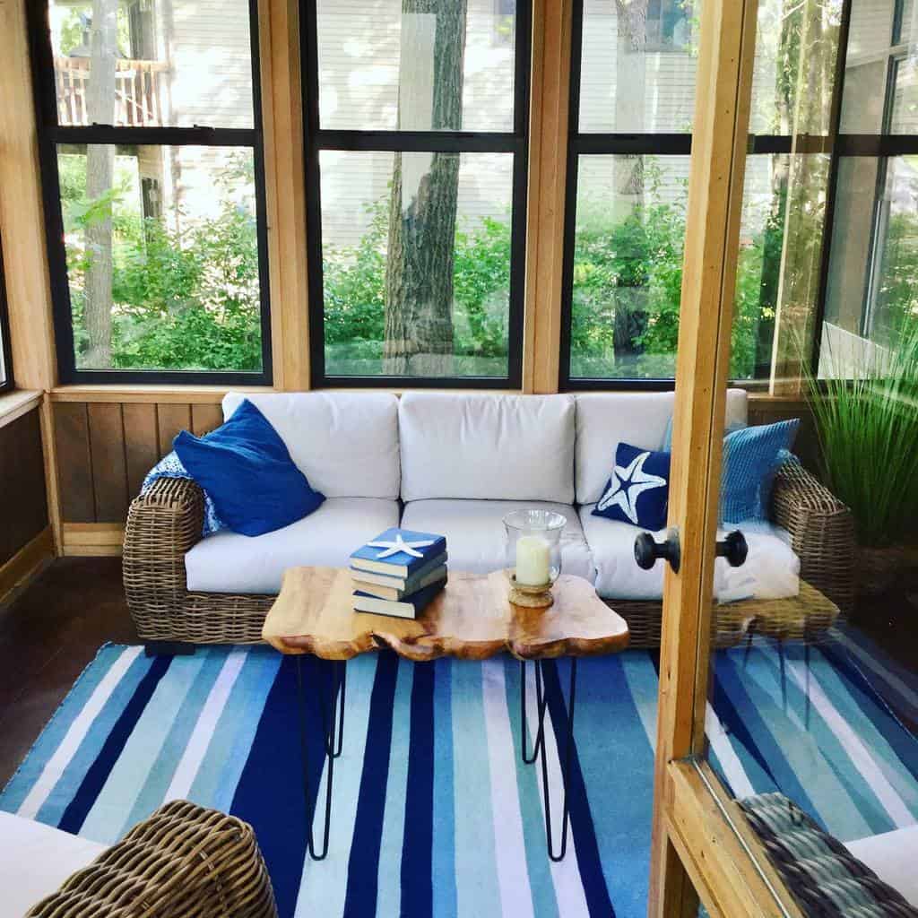 Live-edge wood coffee table with black hairpin legs, styled with books and a candle, set in a cozy sunroom with a nautical theme