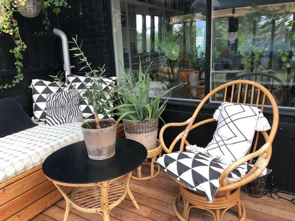 Cozy patio with rattan furniture, potted plants, and geometric-patterned cushions on a wooden deck