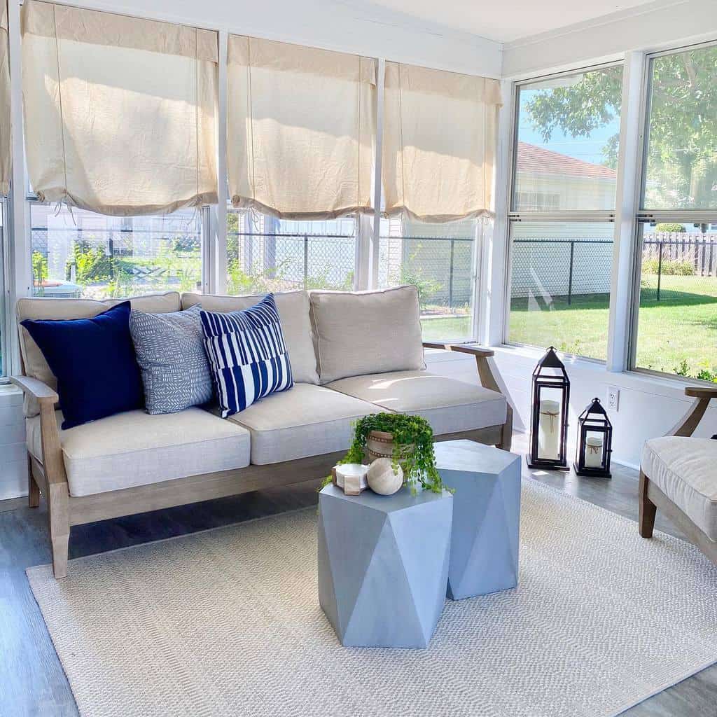 Modern geometric coffee tables in muted blue tones, styled with greenery and candles, set in a bright sunroom with natural light and neutral decor