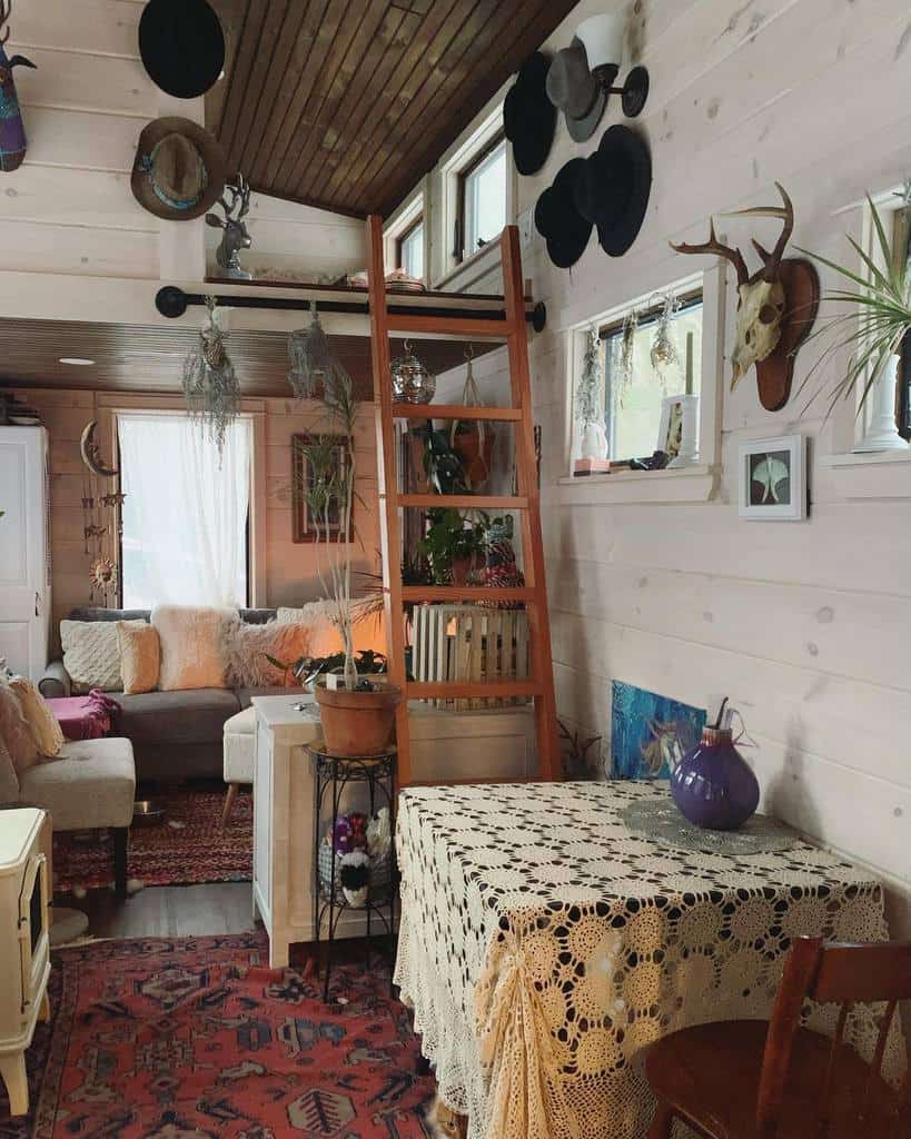 Bohemian tiny home with warm wood tones, eclectic decor, and a cozy loft. Vintage textiles, plants, and hats add personality to the space.