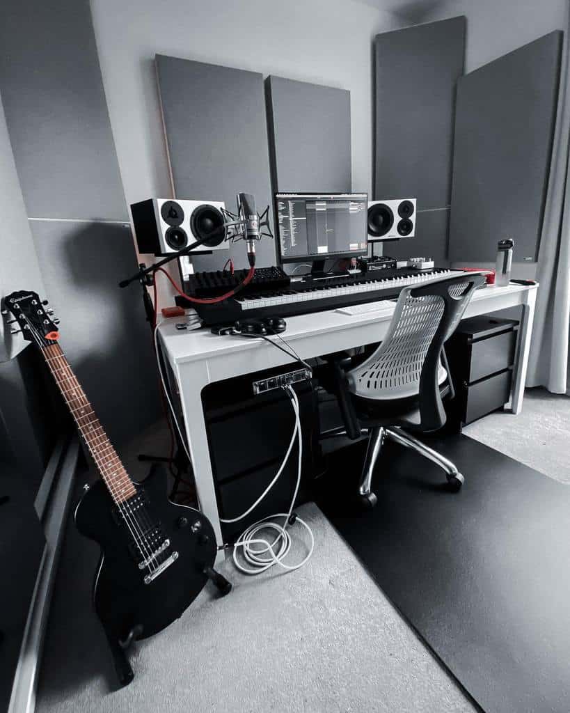 Sleek home music studio with a modern workstation, studio monitors, acoustic panels, a microphone setup, and a black electric guitar