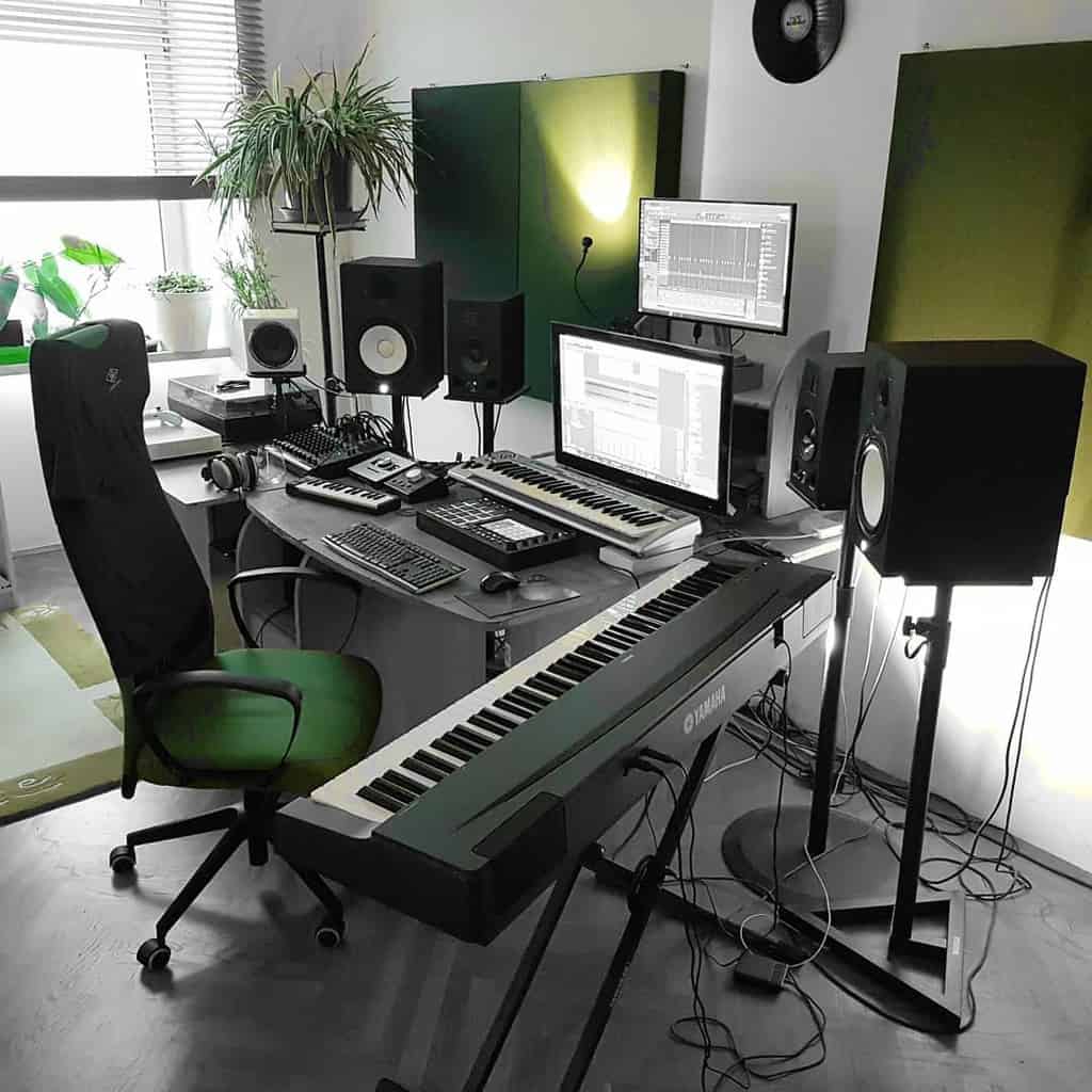 Modern home music studio with dual monitors, MIDI keyboards, studio speakers, acoustic panels, and lush green plants for a creative vibe