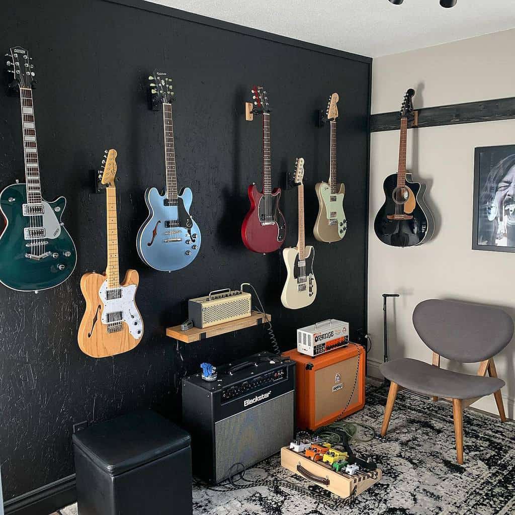 Stylish music room with wall-mounted guitars, amplifiers, a pedalboard, a black accent wall, and a modern lounge chair