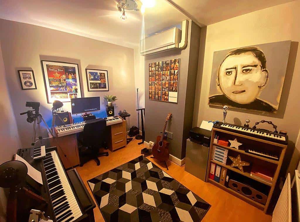 Cozy home music studio with multiple keyboards, a workstation, an acoustic guitar, framed music posters, and warm ambient lighting