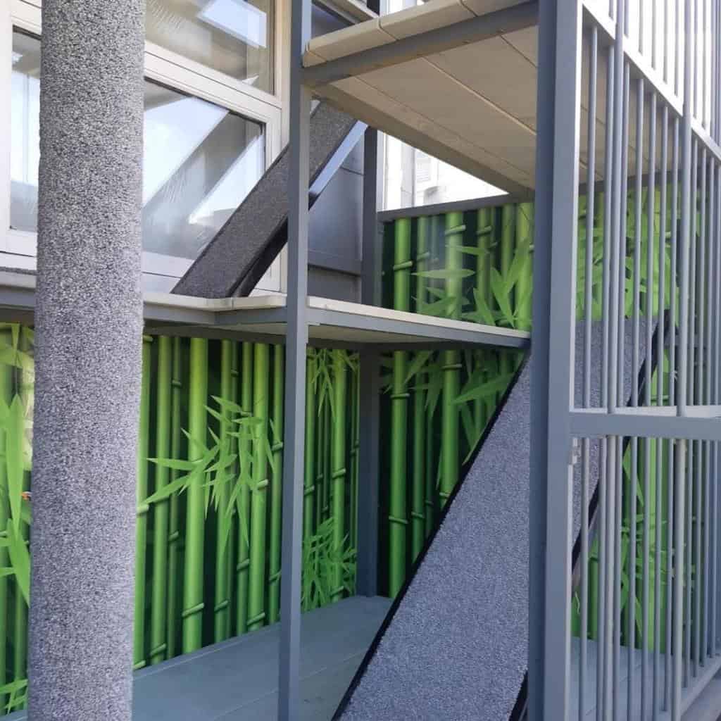 Modern multi-level catio with ramps, platforms, and a bamboo-themed backdrop, providing a stylish and secure outdoor space for cats