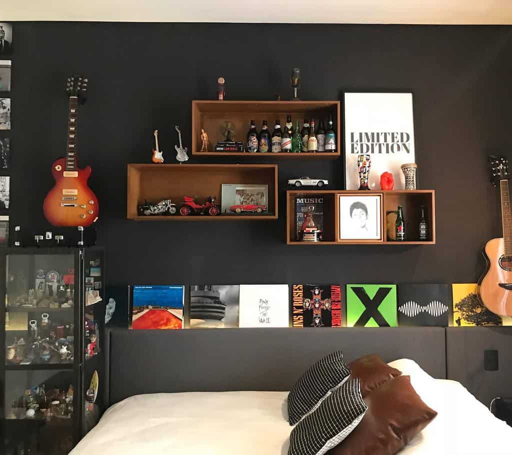 Stylish music-themed bedroom with a dark accent wall, wall-mounted guitars, floating shelves, vinyl records, and a cozy modern bed