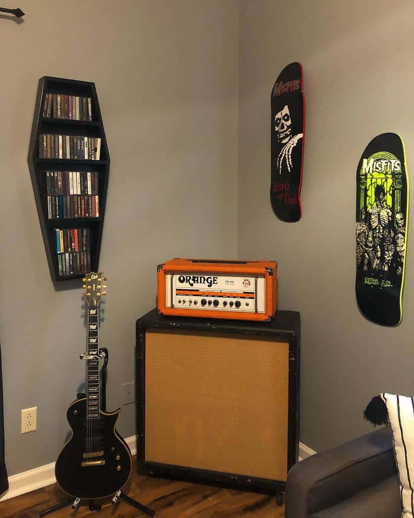 Rock-inspired music room with a black electric guitar, Orange amp, coffin-shaped CD shelf, Misfits-themed skateboards, and dark decor