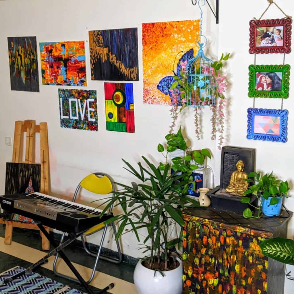 Colorful music room with a Casio keyboard, abstract wall art, potted plants, a decorated cabinet, and a cozy artistic atmosphere