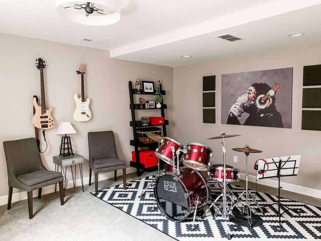 Music room with a drum set on a patterned rug, guitars on the wall, shelves with speakers, and two chairs with a small table