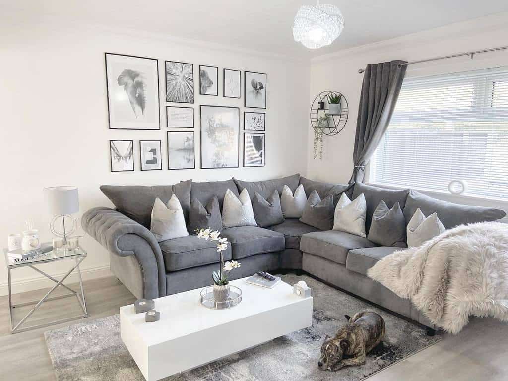 Sleek white rectangular coffee table styled with candles, a tray, and an orchid, set in a modern grey-toned living room with a plush sectional sofa