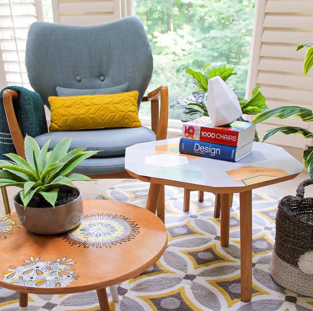 Mid-century modern wooden coffee tables with colorful geometric and floral designs, styled with books, plants, and decor in a vibrant reading nook